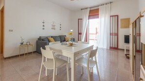 A dining area with a white table and chairs, a sofa, and a decorative wall hanging. - Casa Gaia DX (Porto Cesareo)