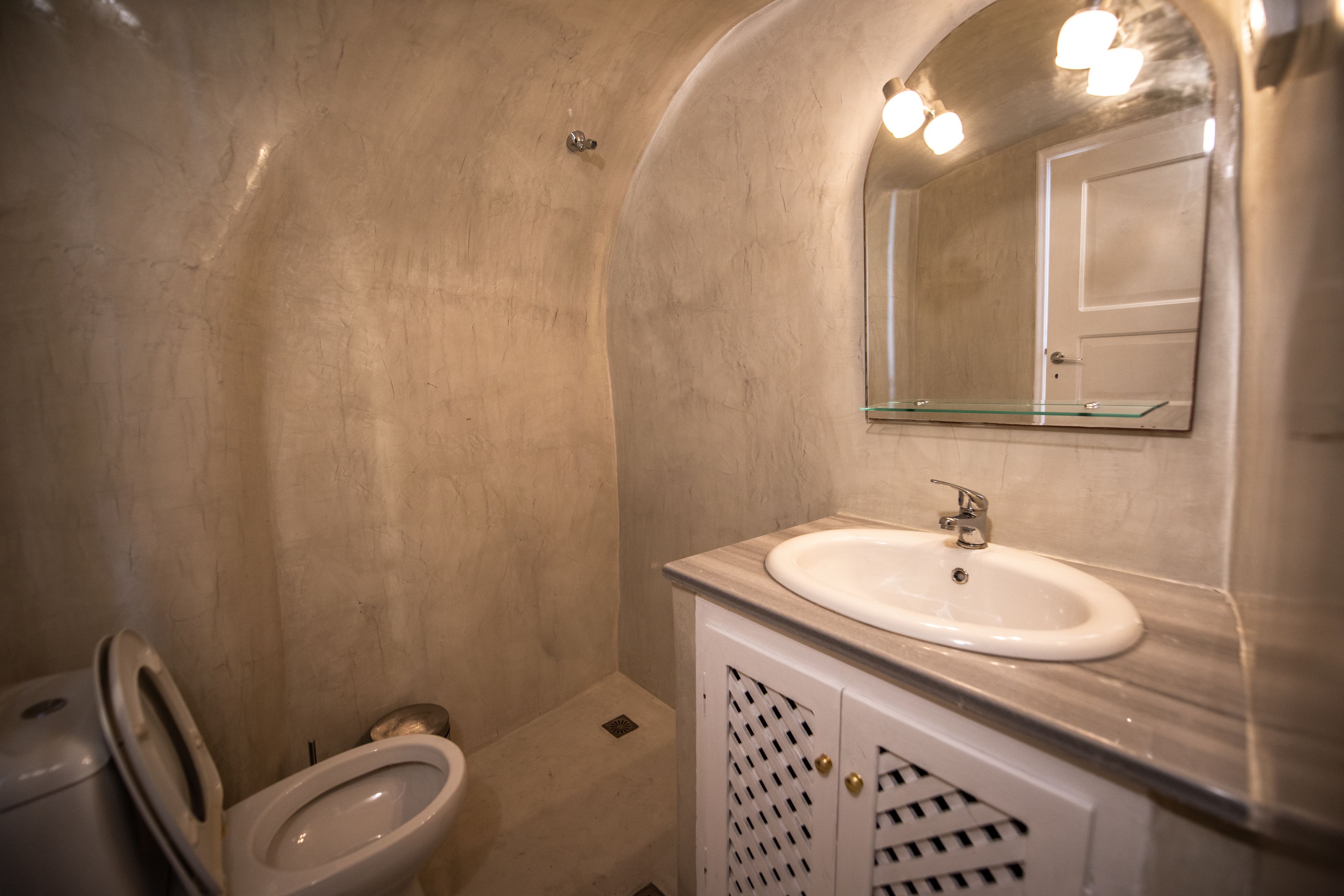 Een badkamer met een wit wastafelmeubel, een spiegelglas en een toilet.