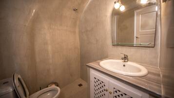 Een badkamer met een wit wastafelmeubel, een spiegelglas en een toilet.