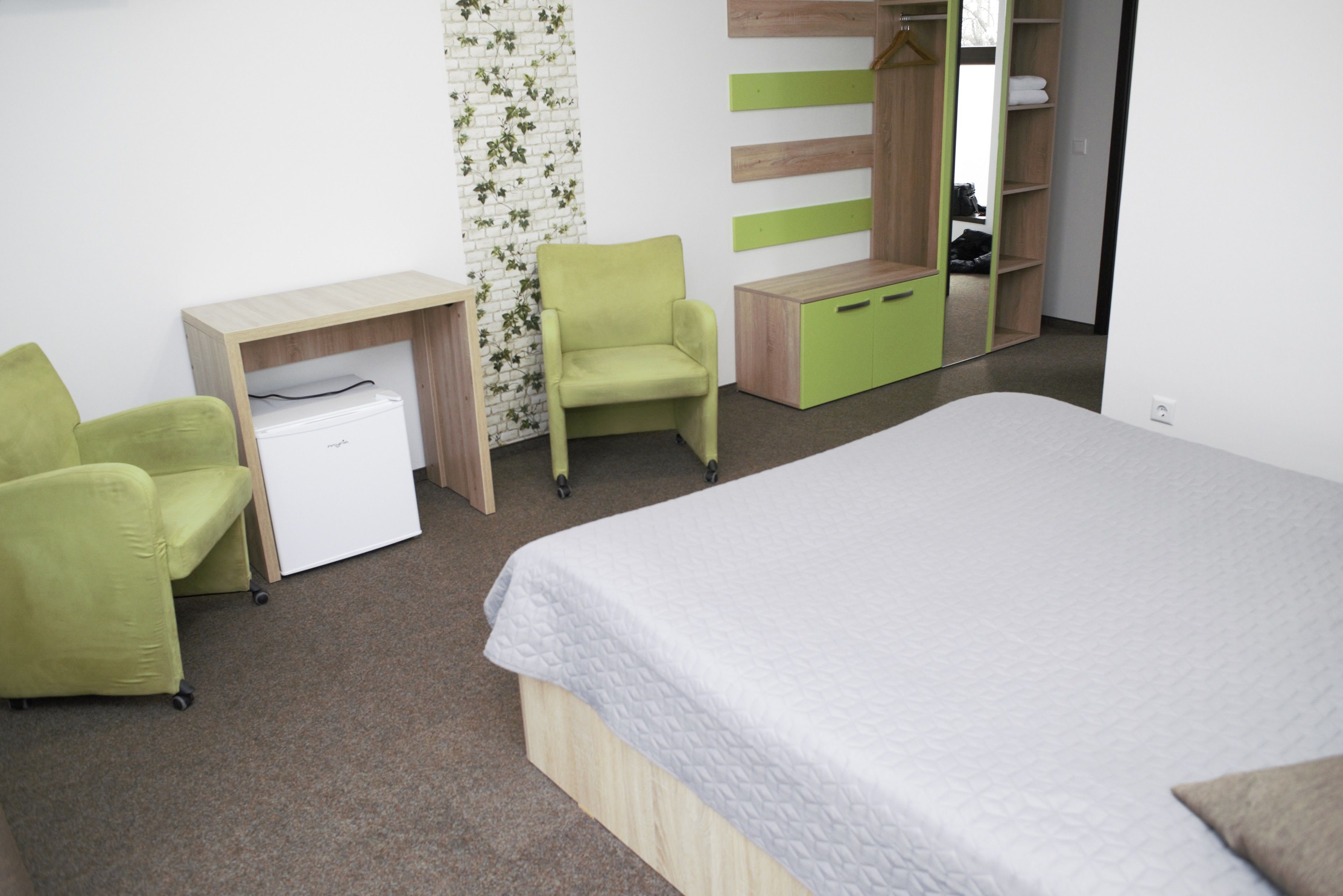 A bedroom with a bed, a desk, a chair, and a wardrobe.