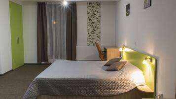 A bedroom with a bed, a chair, a nightstand, a lamp, and a radiator.