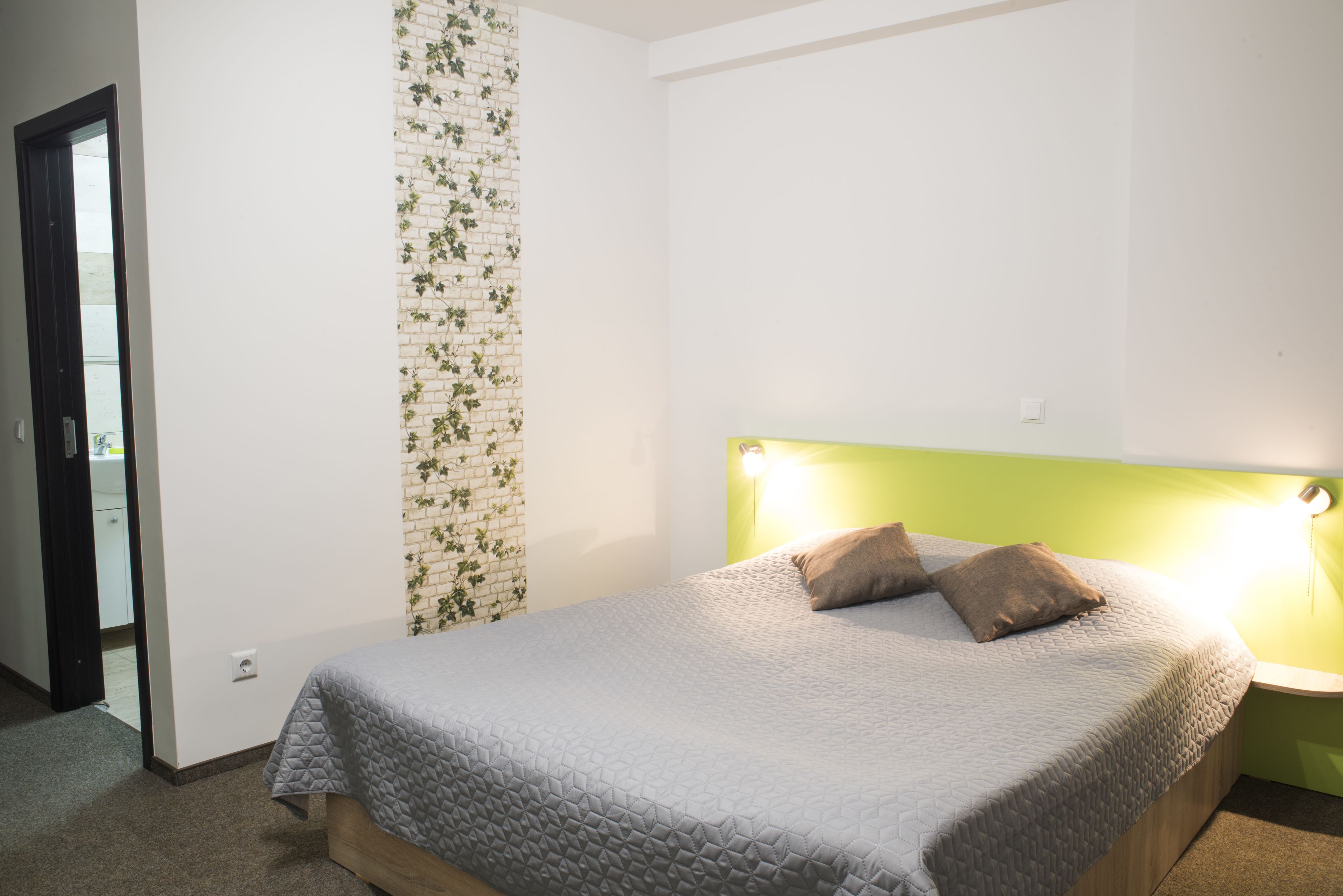 A bedroom with a bed, a headboard, and a wall with a brick pattern.