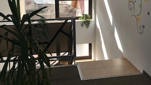 A room with a high ceiling, a large window with a view of mountains, a potted plant, and a wall with floral decals. - Vila William's (Brasov)