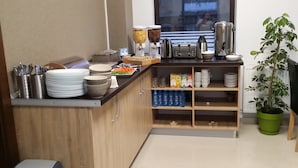 A kitchen area with a coffee station, water dispensers, and a potted plant. - Vila William's (Brasov)