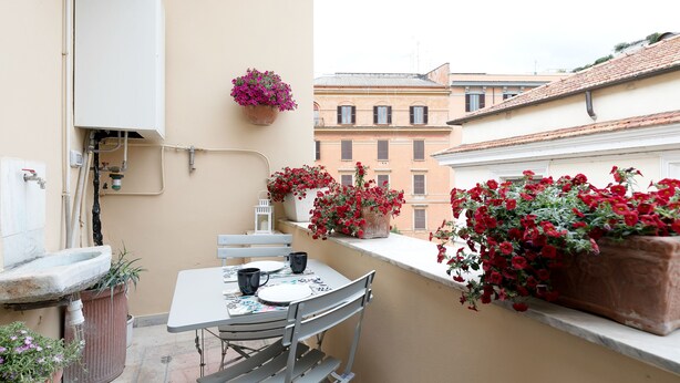 A small balcony with a table and chairs, potted plants, and a water heater. - Vatican Stylish Apartment (Rome)
