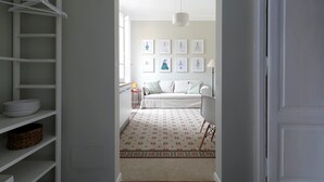 A hallway leading to a living area with a sofa, a lamp, and framed pictures on the wall. - Vatican Stylish Apartment (Rome)