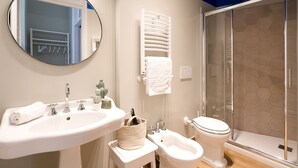 A bathroom with a sink, bidet, toilet, and a glass shower enclosure. - Vatican Stylish Apartment (Rome)