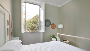 Un dormitorio con cama, ventana, mesita de noche y lámpara.
