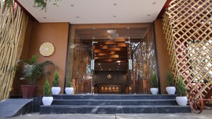 A modern building entrance with a wooden facade, a reception desk, and potted plants. - Raja ka bagh - A Boutique hotel (Nurpur)