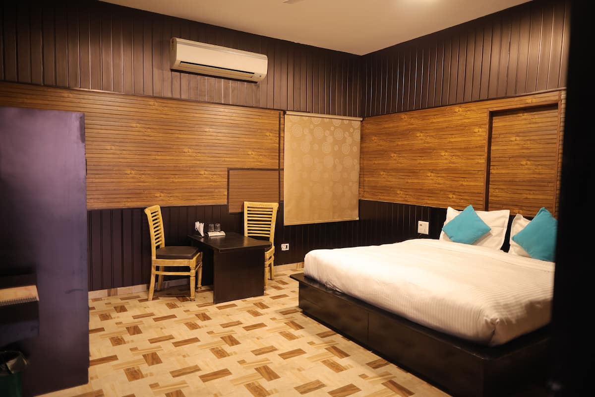 Ein Hotelzimmer mit einem Bett, einem Schreibtisch mit Stuhl und einem Fenster mit Vorhang.