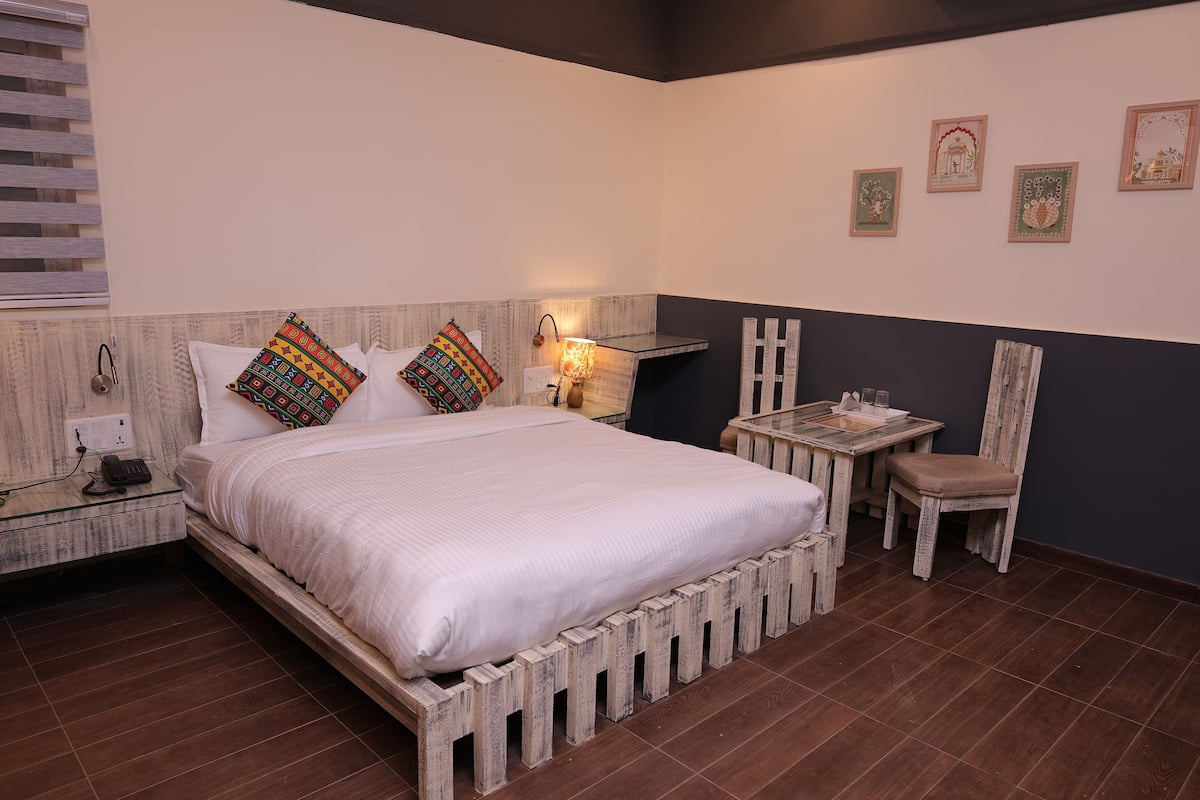 Ein Schlafzimmer mit Bett, Nachttisch, Lampe, Sessel und Wandbild.