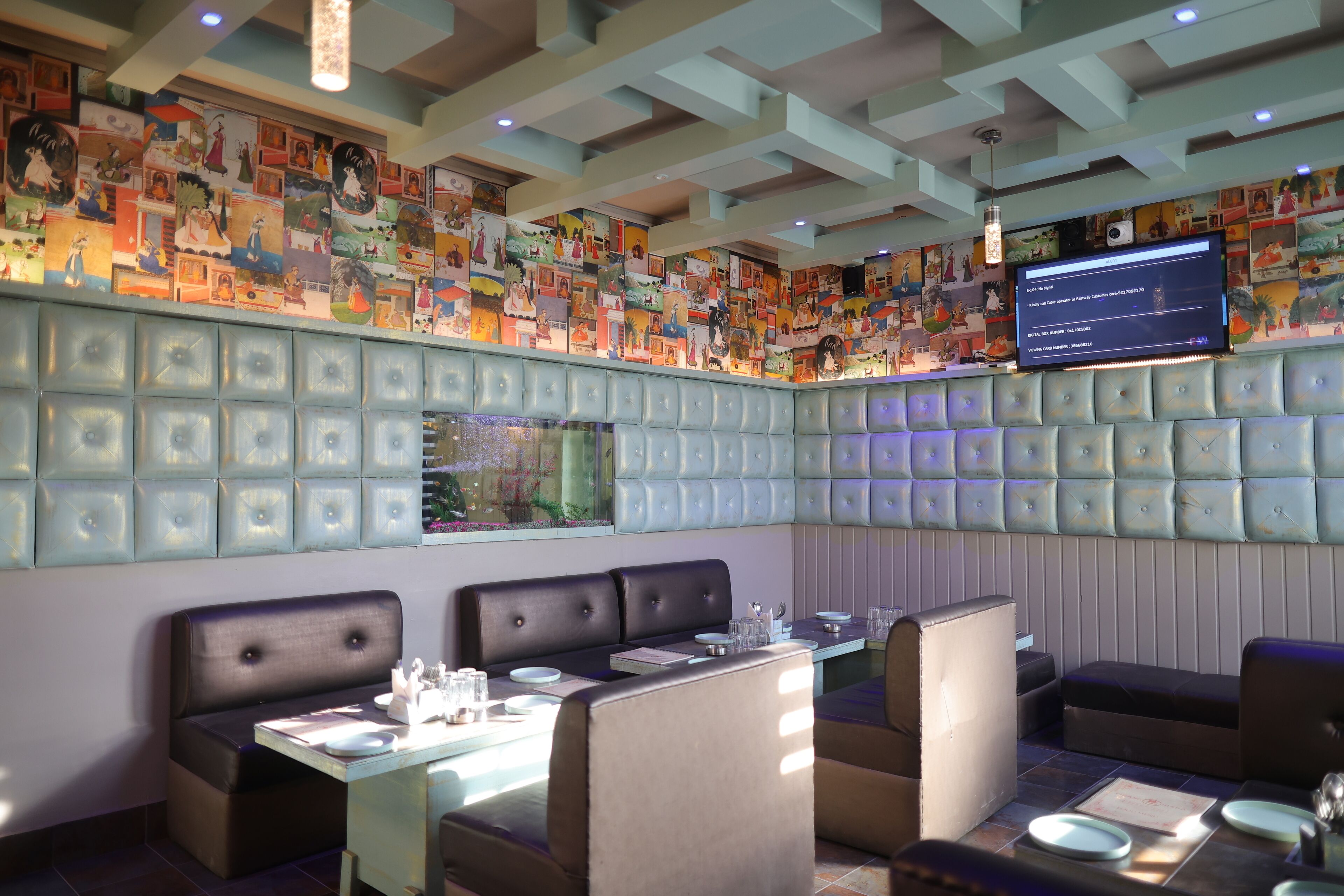 Un restaurante con mesas, cabinas y una pared decorada con ilustraciones coloridas.
