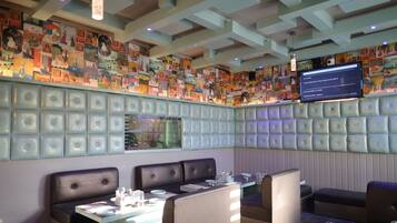 Un restaurante con mesas, cabinas y una pared decorada con ilustraciones coloridas.