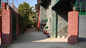 A narrow alleyway with a parked car, brick walls, and a green gate.