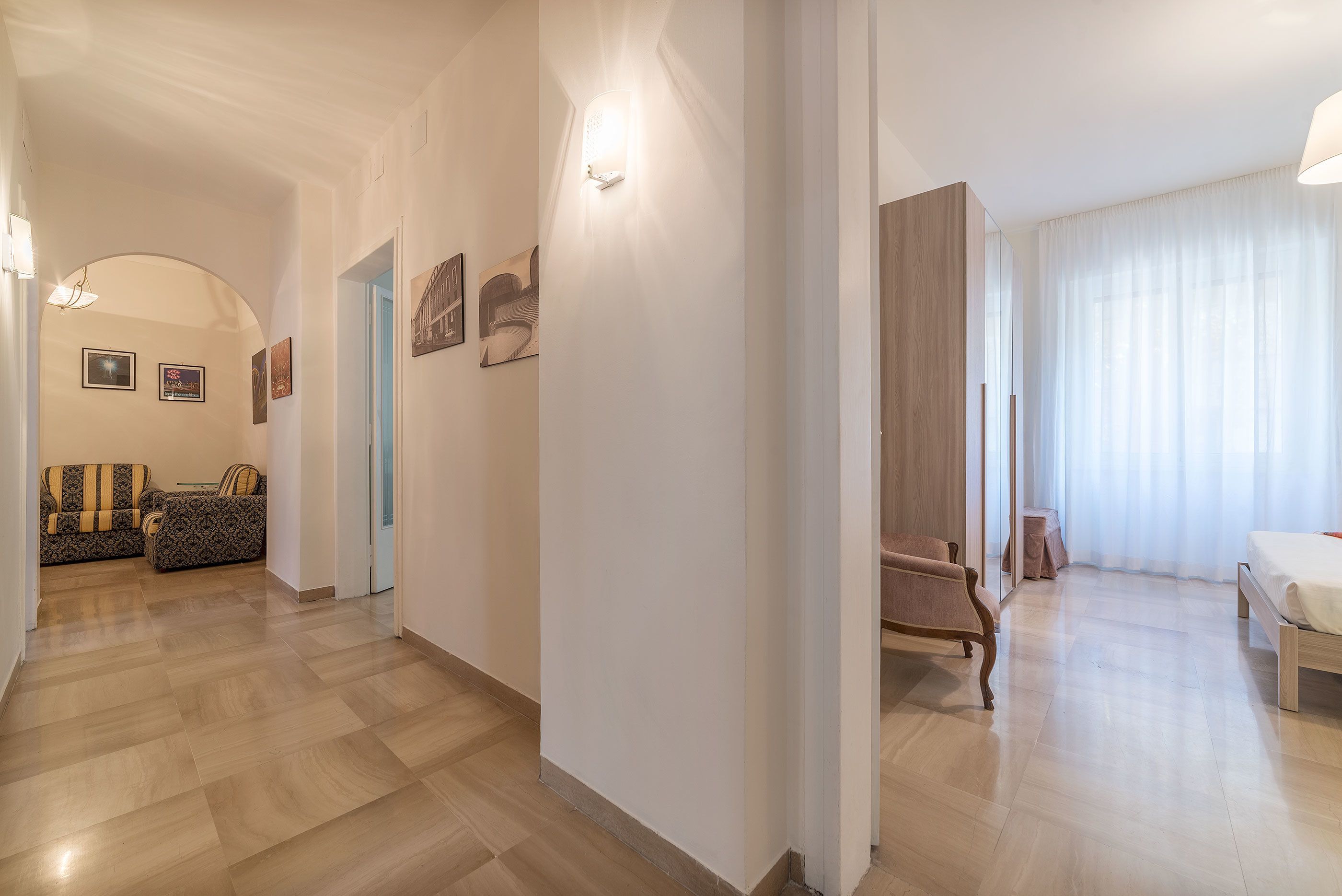 A spacious living area with a wooden floor, a sofa, a chair, and a bed.