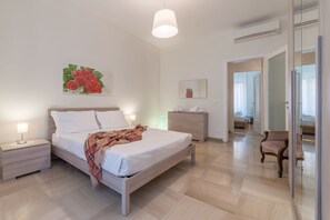 A bedroom with a bed, bedside tables, a nightstand, a dresser, a chair, and a mirror. - Casa della Musica (Rome)