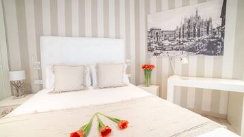 Ein ordentlich eingerichtetes Schlafzimmer mit einem großen Bett, einem Nachttisch, einer Wandlampe und einem gerahmten Bild an der Wand.
