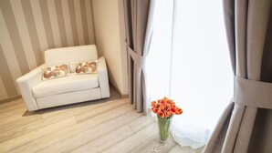 A room with a white sofa, a vase of orange flowers, and striped curtains. - Rooms Milano Duomo (Milan)