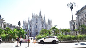 A historic cathedral with intricate Gothic architecture, surrounded by palm trees and a white car parked in front. - Rooms Milano Duomo (Milan)