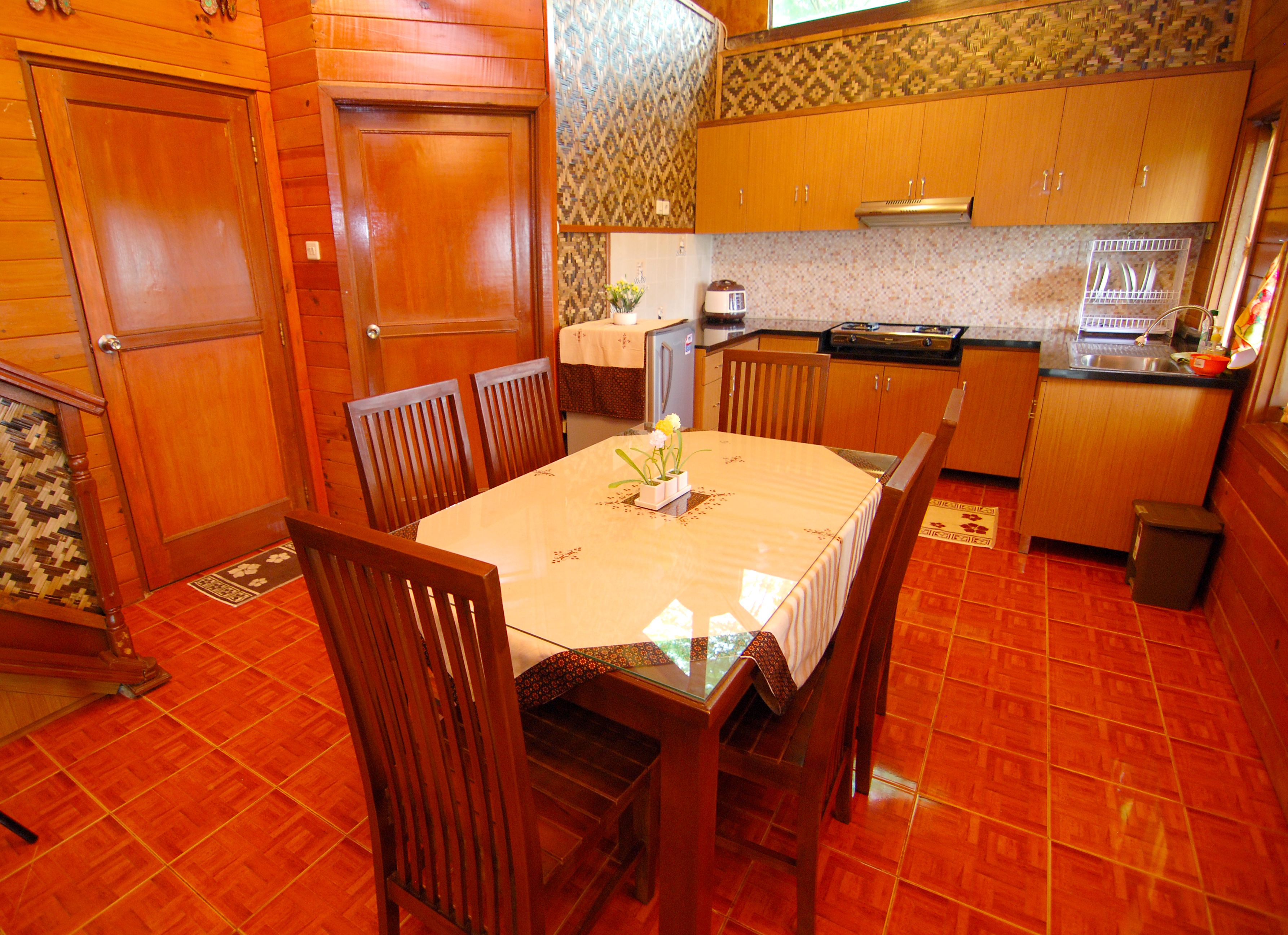 Un comedor con una mesa redonda, sillas de madera y una cocina al fondo.