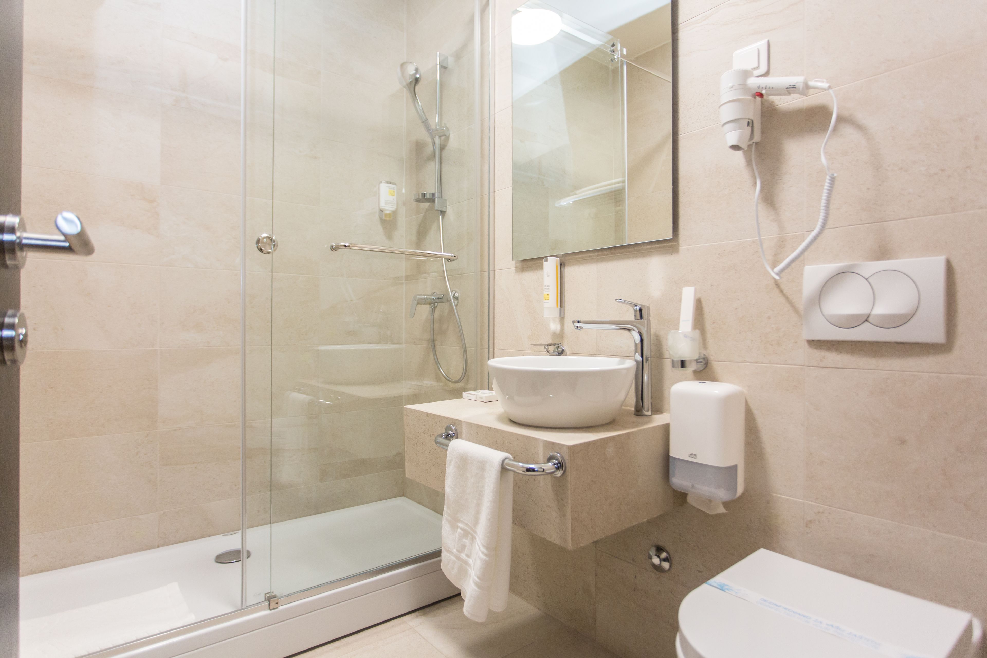 A modern bathroom with a glass shower enclosure, a sink with a mirror above, and a toilet.
