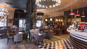 Um restaurante com chão xadrez, várias áreas de estar e lustres pendurados.