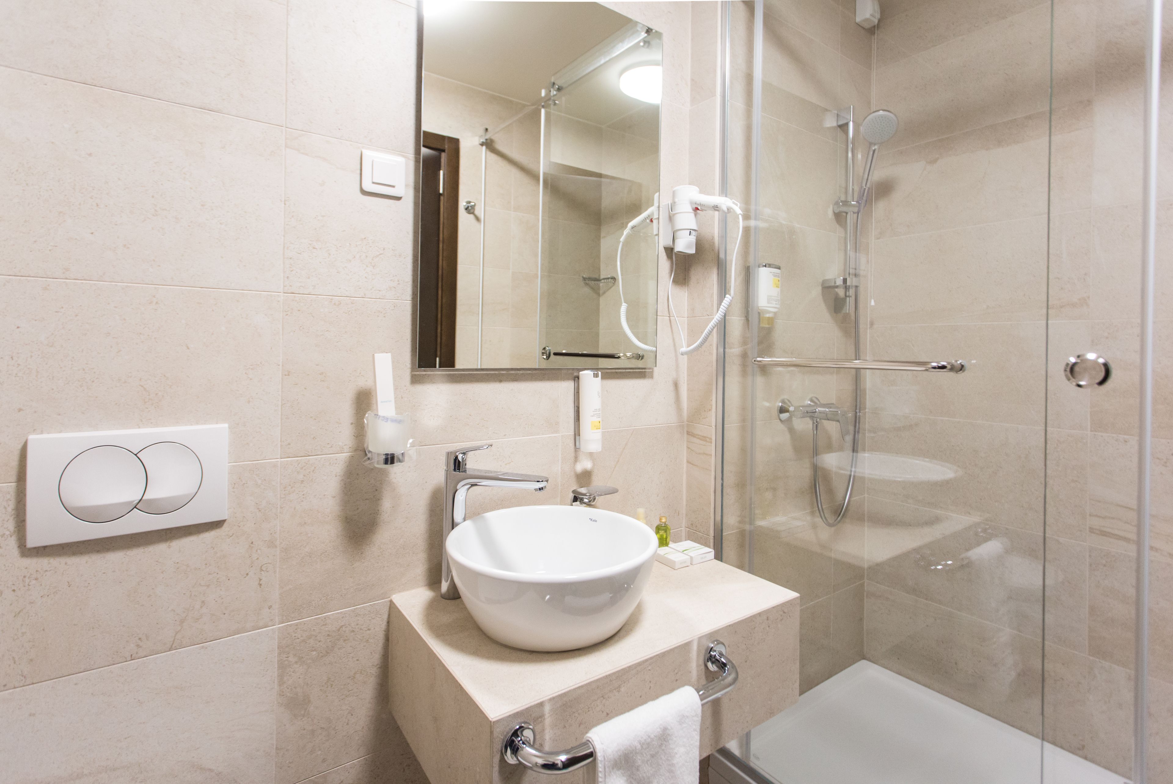 Un baño moderno con ducha de vidrio, un lavabo blanco y un espejo sobre el lavabo.