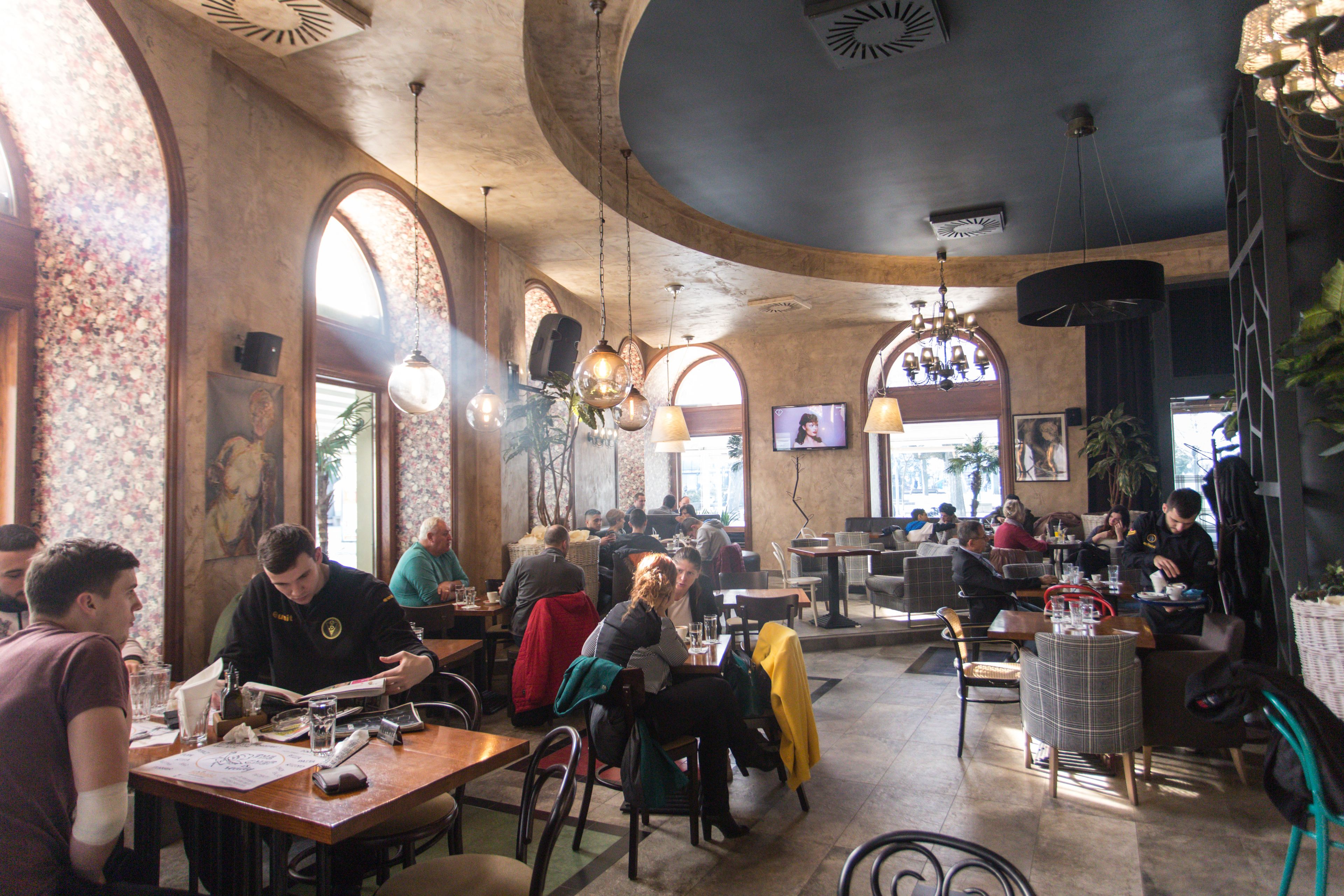 A spacious restaurant with high ceilings, arched windows, and multiple seating areas.