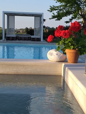 A swimming pool with a white stone and a terracotta pot with red flowers. - Le MaRaClà Country House (Jesi)