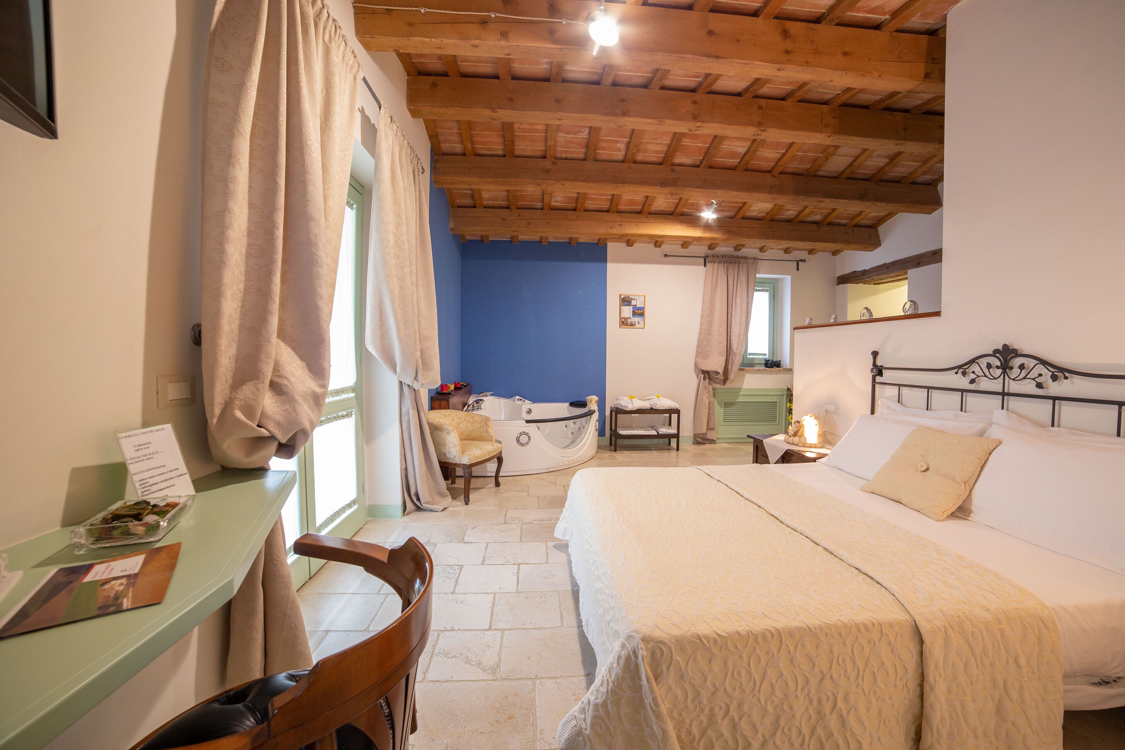 Une chambre à coucher avec un lit, un bureau, une chaise, une baignoire et une fenêtre avec des rideaux.