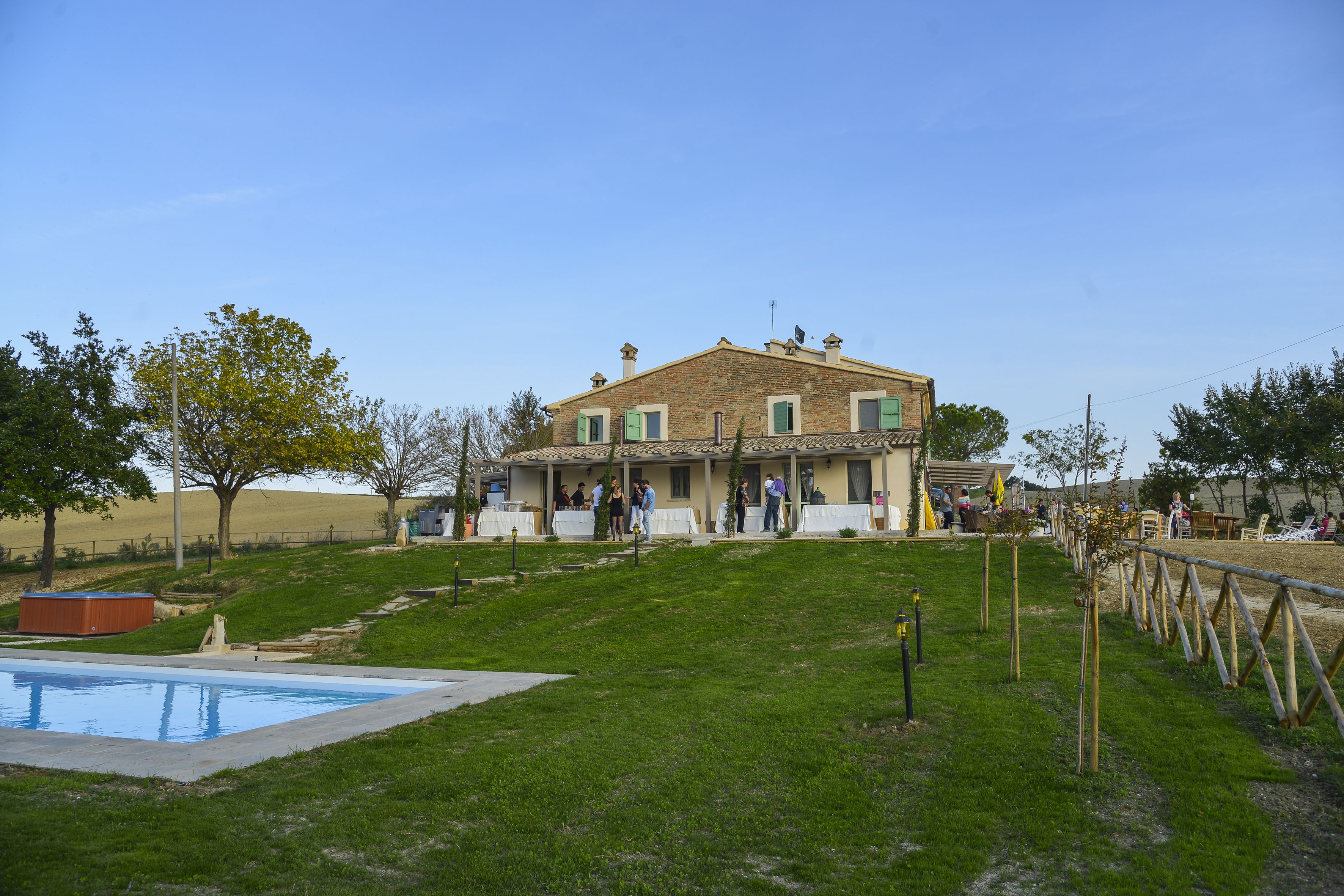 A two-story house with a swimming pool, a grassy yard, and a wooden fence.