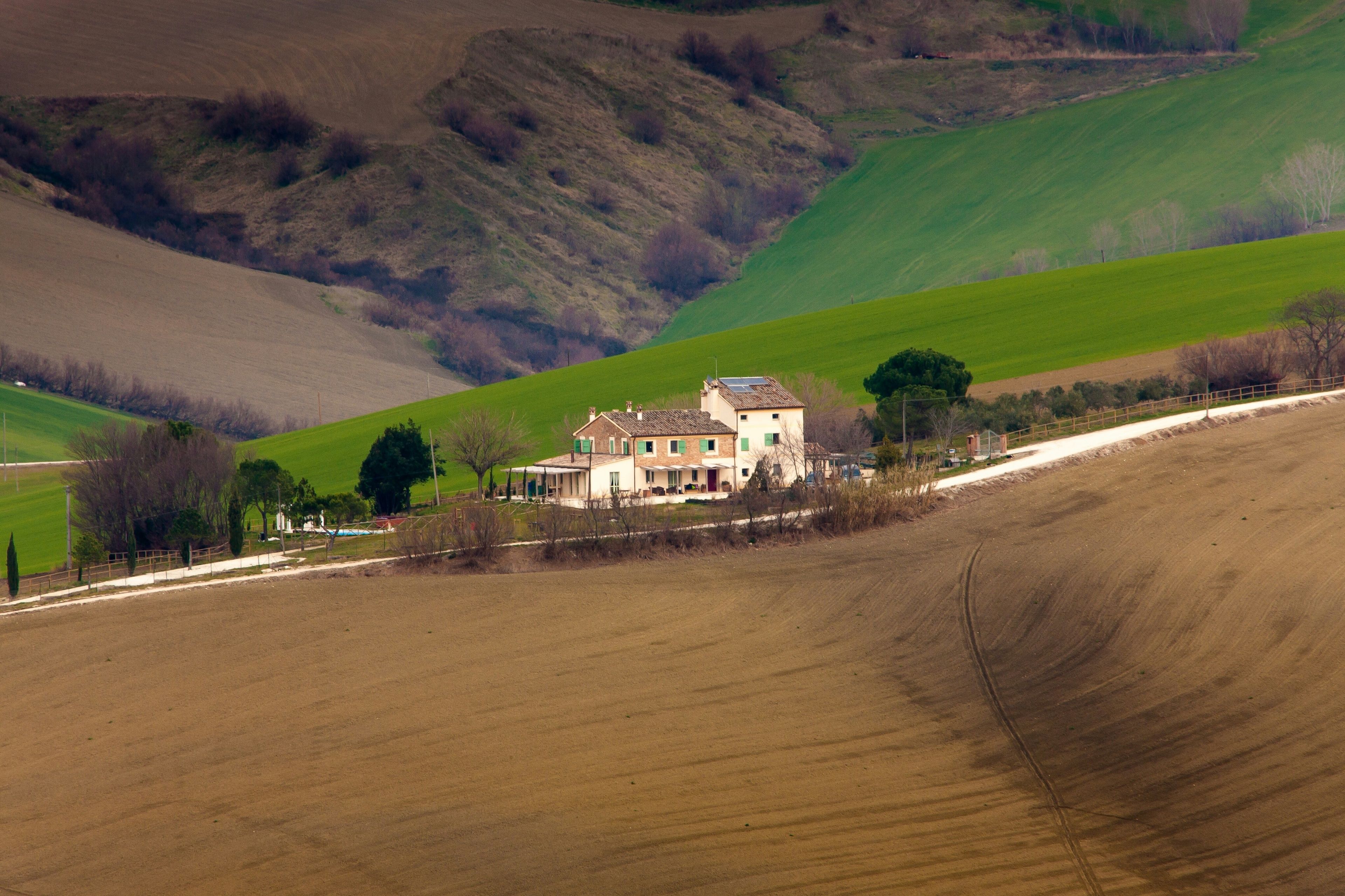 Une maison de campagne avec un grand jardin et une vue sur des collines ondoyantes.