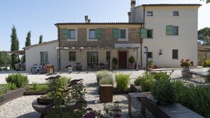 Una casa de dos plantas con un patio, mobiliario exterior y un camino de grava.