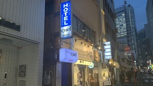 A hotel with a blue sign, a white sign with Japanese characters, and a storefront with a wooden fence. - Hotel Owl Tokyo Shinbashi (Tokyo)
