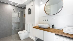 A modern bathroom with a glass-enclosed shower, a white toilet, a wooden vanity with a sink, and a mirror. - Super-Apartamenty Exotic (Poznan)