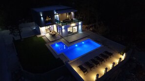 A modern two-story house with a swimming pool and outdoor seating area.