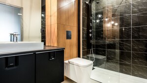 A modern bathroom with a black marble shower, a white toilet, and a black cabinet. - Super-Apartamenty Exclusive (Poznan)