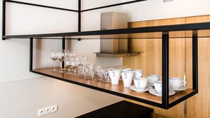 A kitchen with a wooden countertop, black metal shelving, and various glassware and white cups. - Super-Apartamenty Exclusive (Poznan)
