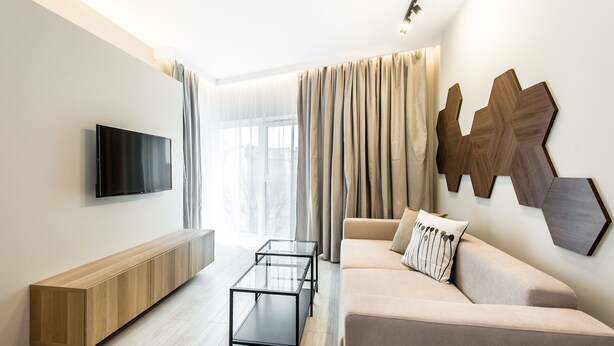 A modern living room with a flat-screen TV, a sofa, a coffee table, and a built-in bench. - Super-Apartamenty Exclusive (Poznan)