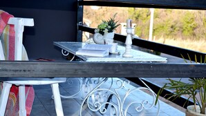 Ein Balkon mit Tisch, Stuhl, Blumentopf und einer dekorativen Kerzenhalterung.
