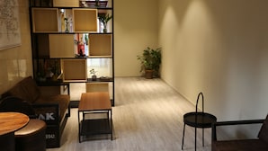 A modern living room with a sofa, a wooden coffee table, a bookshelf, and a potted plant. - Shanghai Jiejia Preferred Hotel (Shanghai)