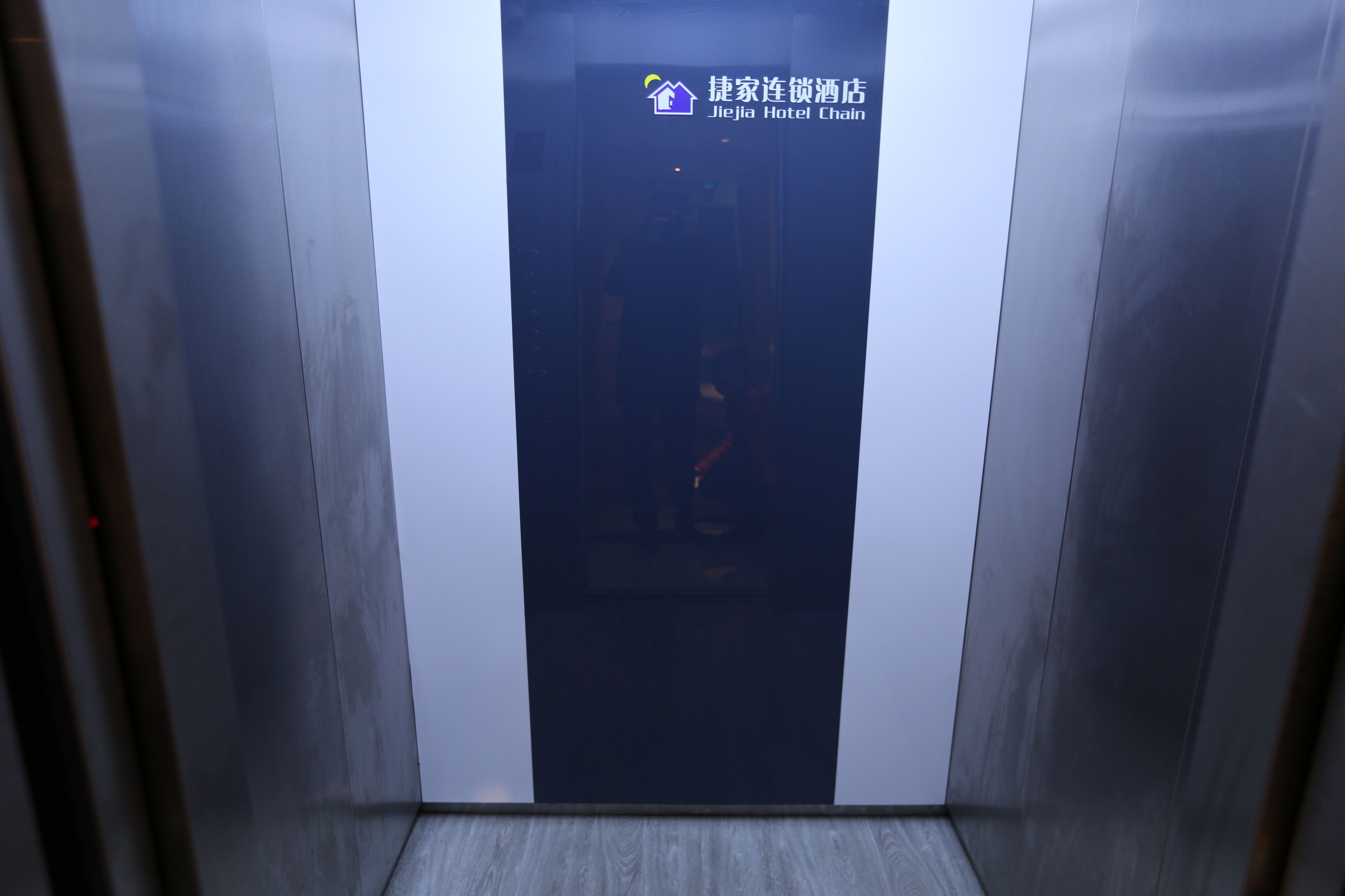 An elevator interior with a logo for Jiejia Hotel Chain on the wall.