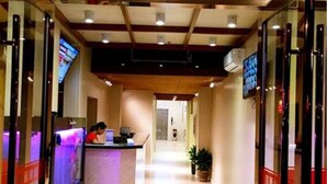A hotel reception area with a reception desk, a TV screen, and a potted plant. - Shanghai Jiejia Preferred Hotel (Shanghai)