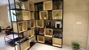 A modern interior with a black and beige shelving unit containing various items, including plants and a coffee machine. - Shanghai Jiejia Preferred Hotel (Shanghai)