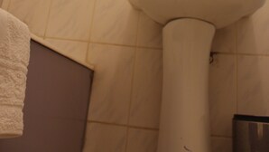 Un bagno con un lavandino bianco, un asciugamano appeso al muro e un water.