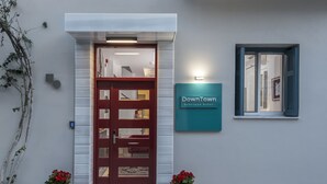 A hotel entrance with a red door, a sign reading "DownTown boutique hotel," and two potted plants. - DownTown Hotel (Nafplio)