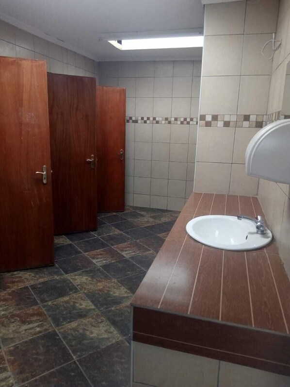 Un baño con lavamanos, paredes de azulejos y puertas de madera.