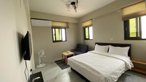 A modern hotel room with a large bed, a flat-screen TV mounted on the wall, a desk with a chair, and a ceiling fan. - Home of 120 B&B (Jiaoxi)