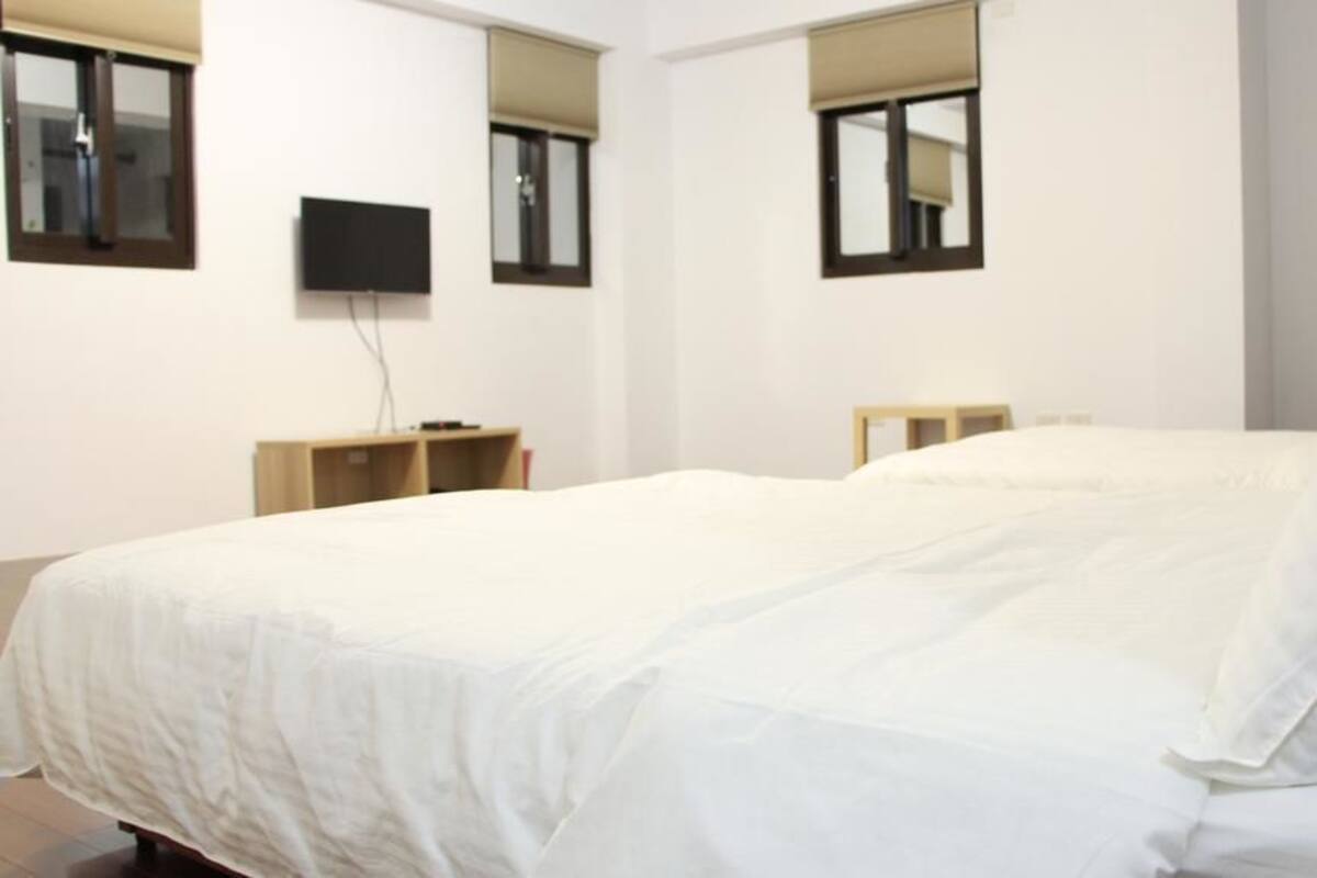 Ein Hotelzimmer mit einem großen Bett, einem flachbildfernseher an der Wand und einem kleinen Holfnichtschrank.