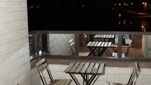 An outdoor patio with wooden tables and chairs, a brick wall, and a view of the city at night. - Home of 120 B&B (Jiaoxi)